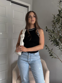 Model wearing the Jolie Contrast Trim Knit Halter Top in black with white piping, styled with light wash jeans, spring outfit