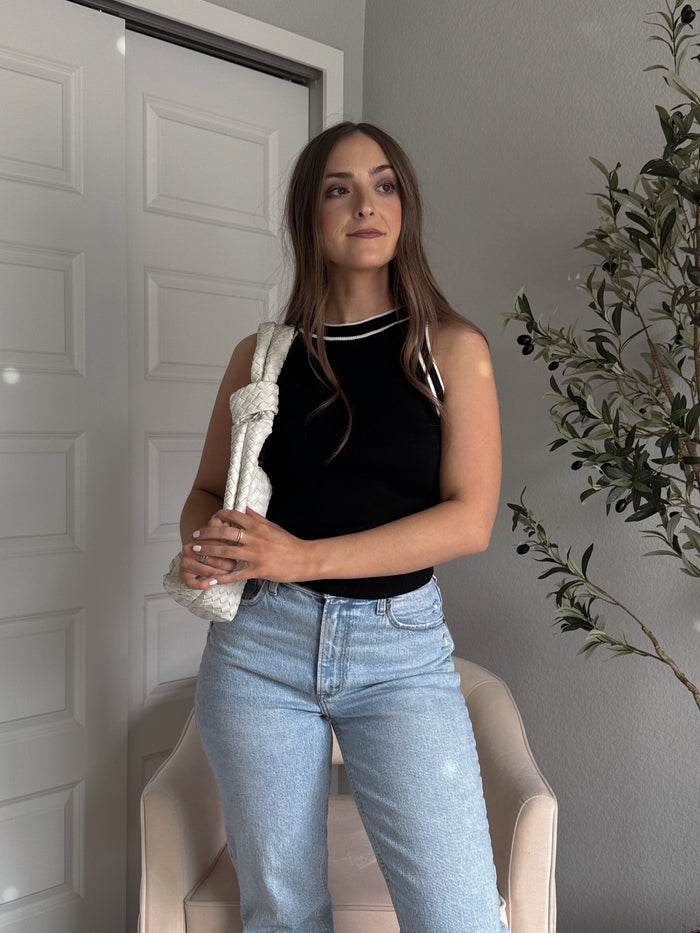 Model wearing the Jolie Contrast Trim Knit Halter Top in black with white piping, styled with light wash jeans, spring outfit