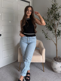 Model wearing the Jolie Contrast Trim Knit Halter Top in black with white piping, styled with light wash jeans, spring outfit