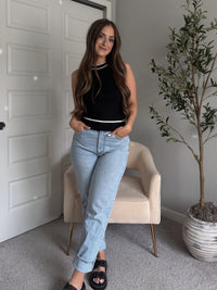 Model wearing the Jolie Contrast Trim Knit Halter Top in black with white piping, styled with light wash jeans, spring outfit