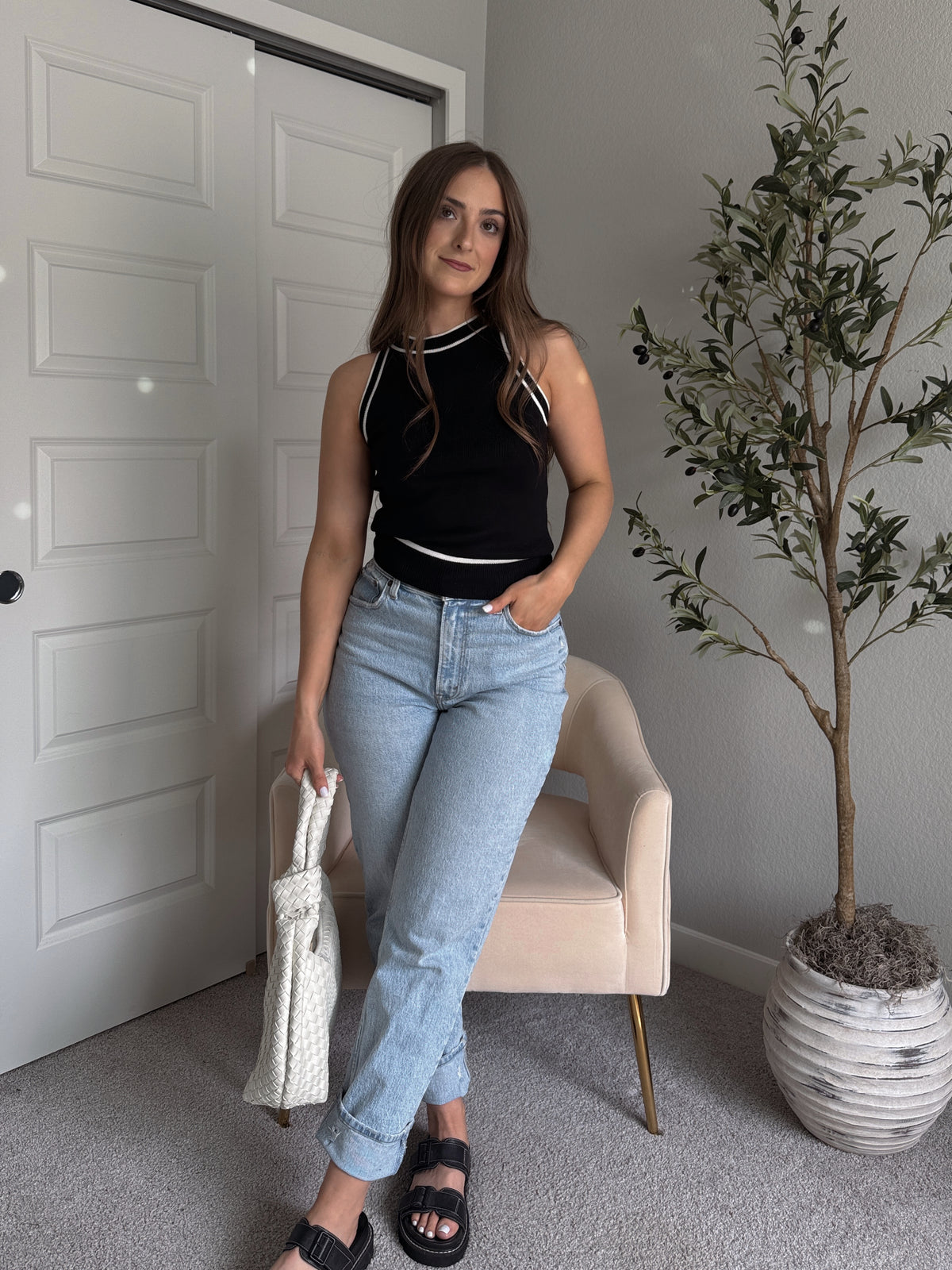 Model wearing the Jolie Contrast Trim Knit Halter Top in black with white piping, styled with light wash jeans, spring outfit