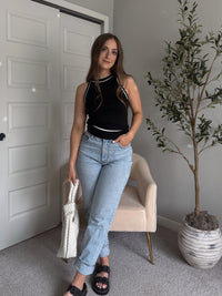 Model wearing the Jolie Contrast Trim Knit Halter Top in black with white piping, styled with light wash jeans, spring outfit