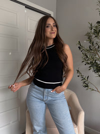 Model wearing the Jolie Contrast Trim Knit Halter Top in black with white piping, styled with light wash jeans, spring outfit