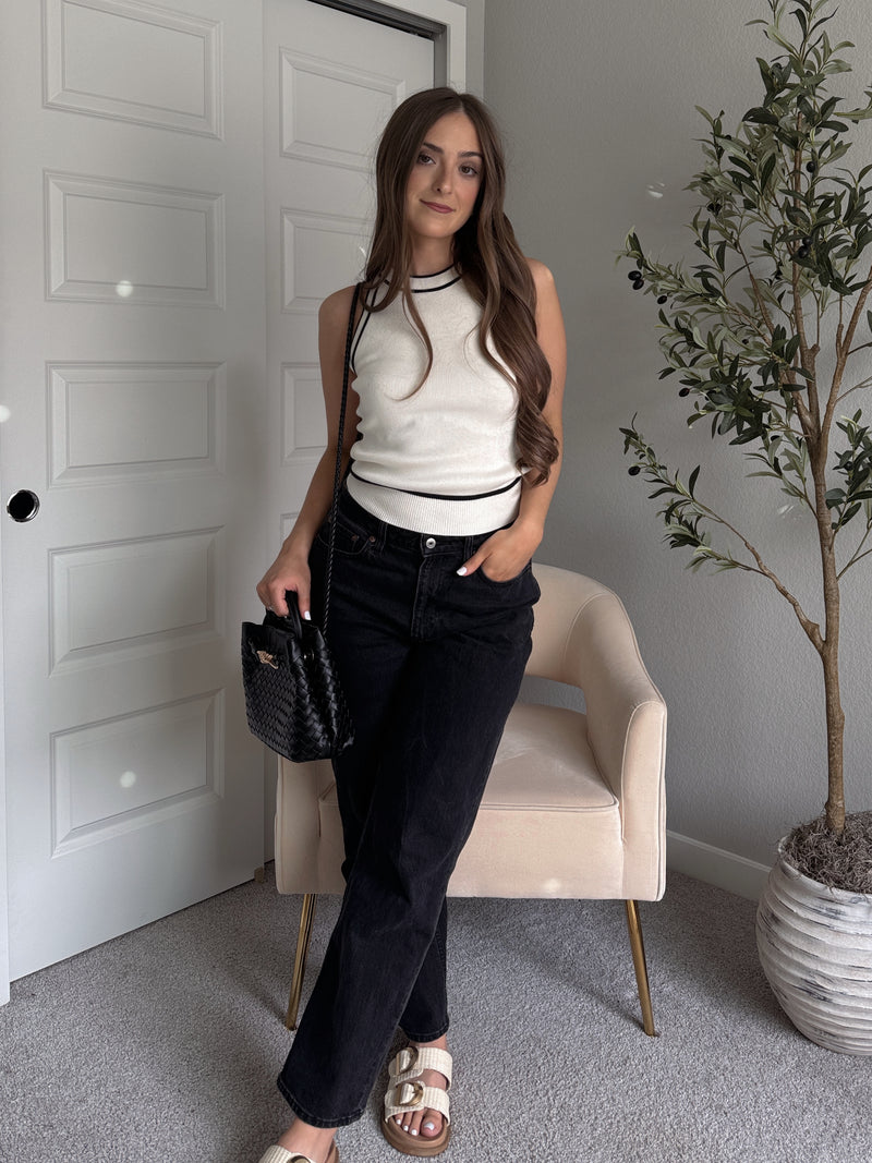 Model wearing the Jolie Contrast Trim Knit Halter Top in ivory with black piping, styled with black wash jeans, spring outfit