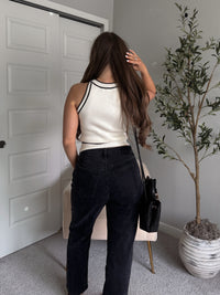 Model wearing the Jolie Contrast Trim Knit Halter Top in ivory with black piping, styled with black wash jeans, spring outfit