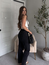 Model wearing the Jolie Contrast Trim Knit Halter Top in ivory with black piping, styled with black wash jeans, spring outfit