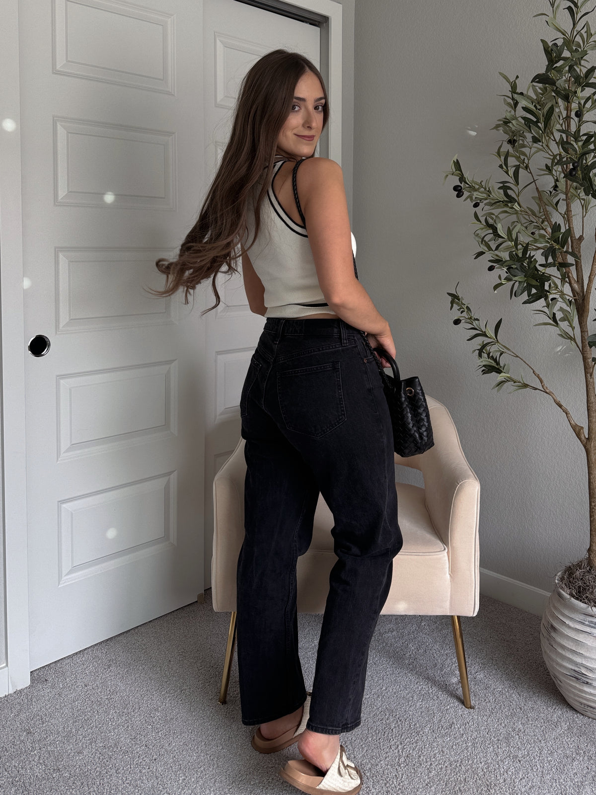 Model wearing the Jolie Contrast Trim Knit Halter Top in ivory with black piping, styled with black wash jeans, spring outfit