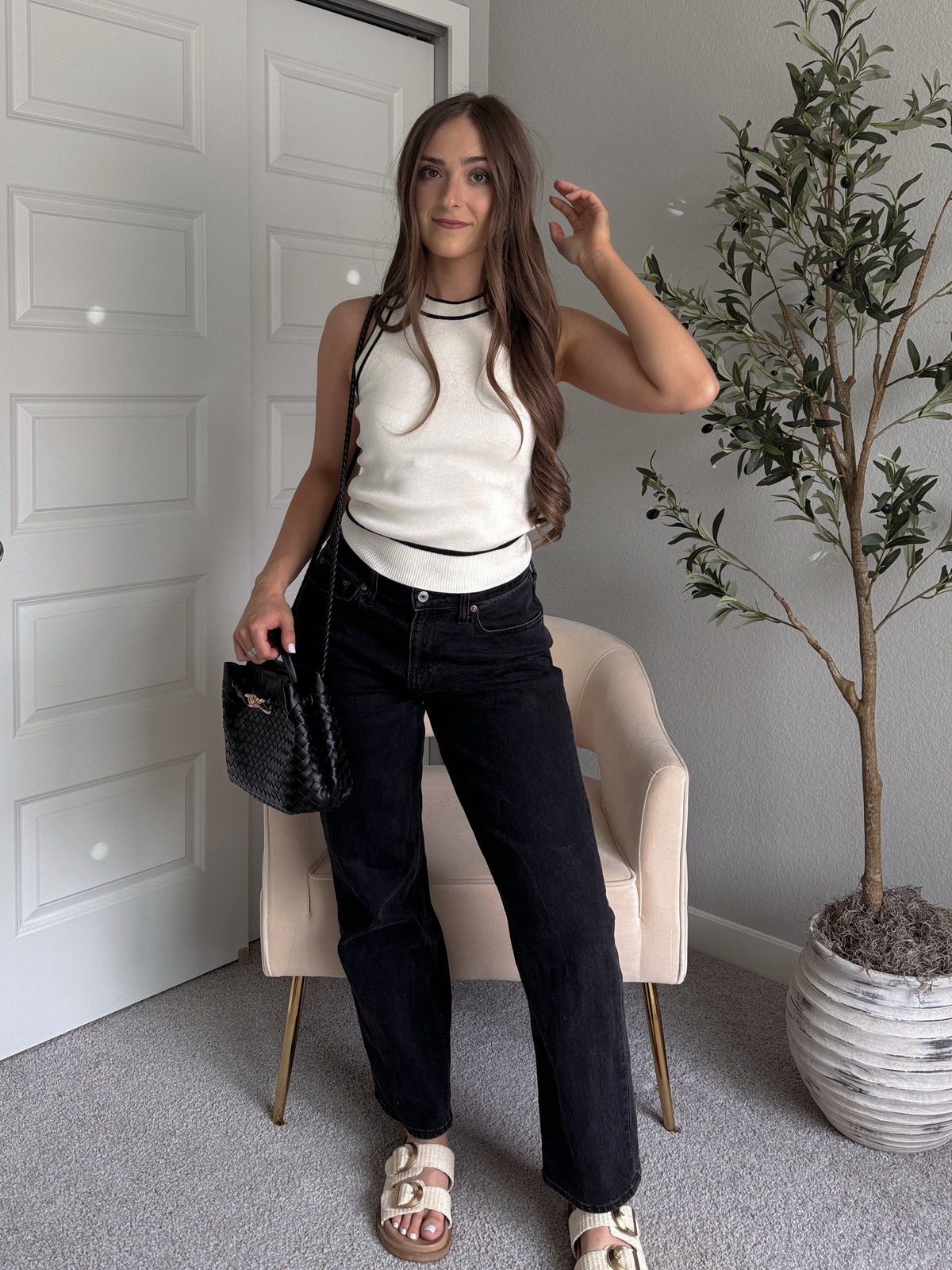 Model wearing the Jolie Contrast Trim Knit Halter Top in ivory with black piping, styled with black wash jeans, spring outfit