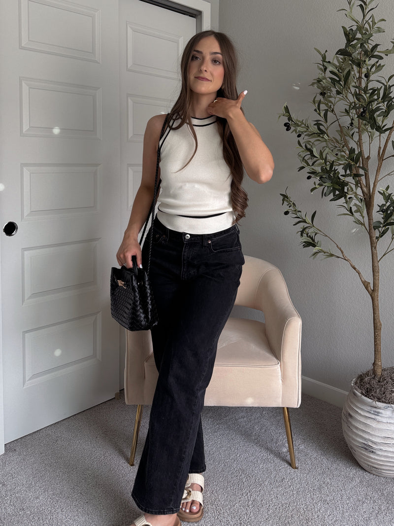 Model wearing the Jolie Contrast Trim Knit Halter Top in ivory with black piping, styled with black wash jeans, spring outfit