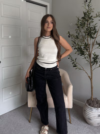 Model wearing the Jolie Contrast Trim Knit Halter Top in ivory with black piping, styled with black wash jeans, spring outfit