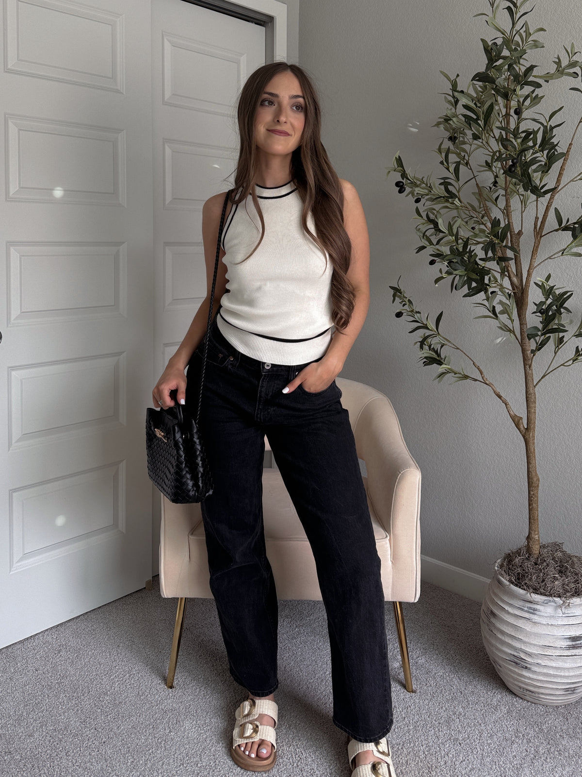Model wearing the Jolie Contrast Trim Knit Halter Top in ivory with black piping, styled with black wash jeans, spring outfit